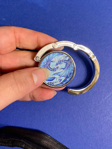 Blue dragon business hand bag hanger, keep in your handbag, unfurl hook to hang you hand bag form cafe or restaurant table. Keeps bag of the dirty floor and safe in your line of vision.